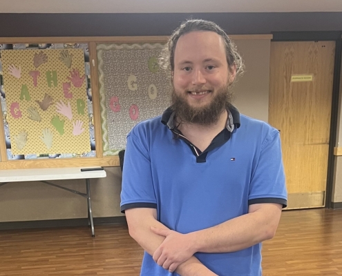 A man named Kinzer who graduated the Hillcrest Platte County HPC Transitional Housing Program Standing by his graduation cake smiling
